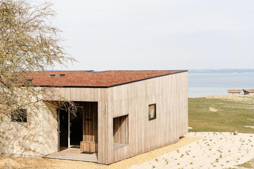 a small house with a red roof on a beach at Enjoy Twosomeness With A View Of Helnæs in Ebberup