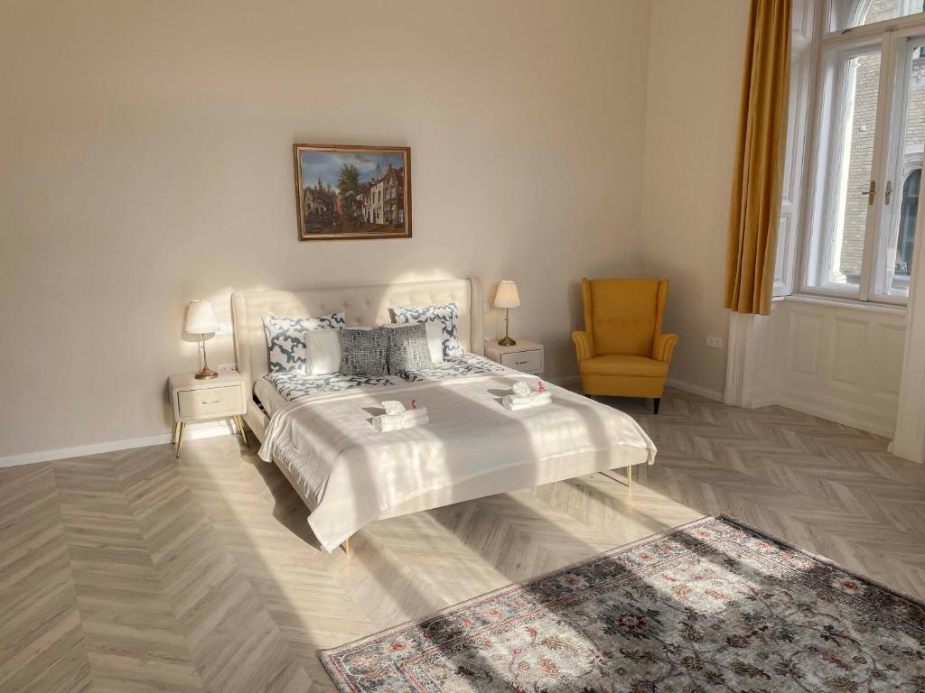 a white bedroom with a bed and a chair at Luxury Apartment Opposite Budapest Opera, Central, AC, Metro 1, Sleeps 6 in Budapest