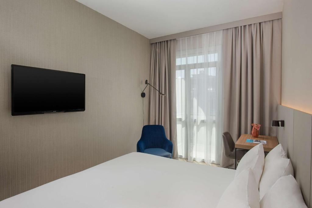 a hotel room with a bed and a television at NH Trieste in Trieste
