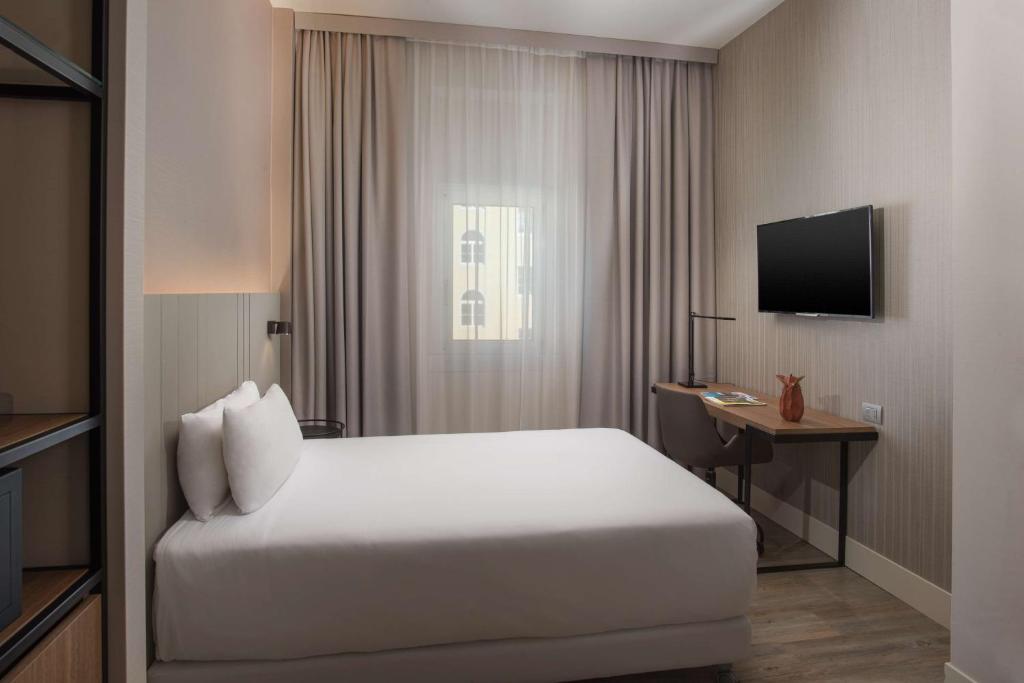 a hotel room with a bed and a television at NH Trieste in Trieste