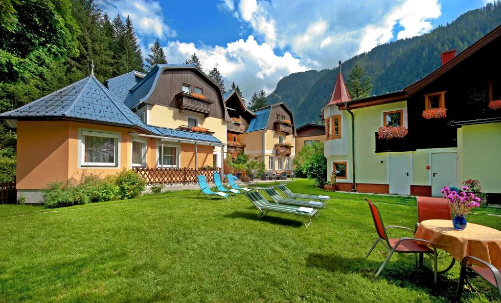 einen Garten mit Stühlen und Tischen und ein Haus in der Unterkunft GRUBERS, Hotel Appartments Gastein in Bad Gastein