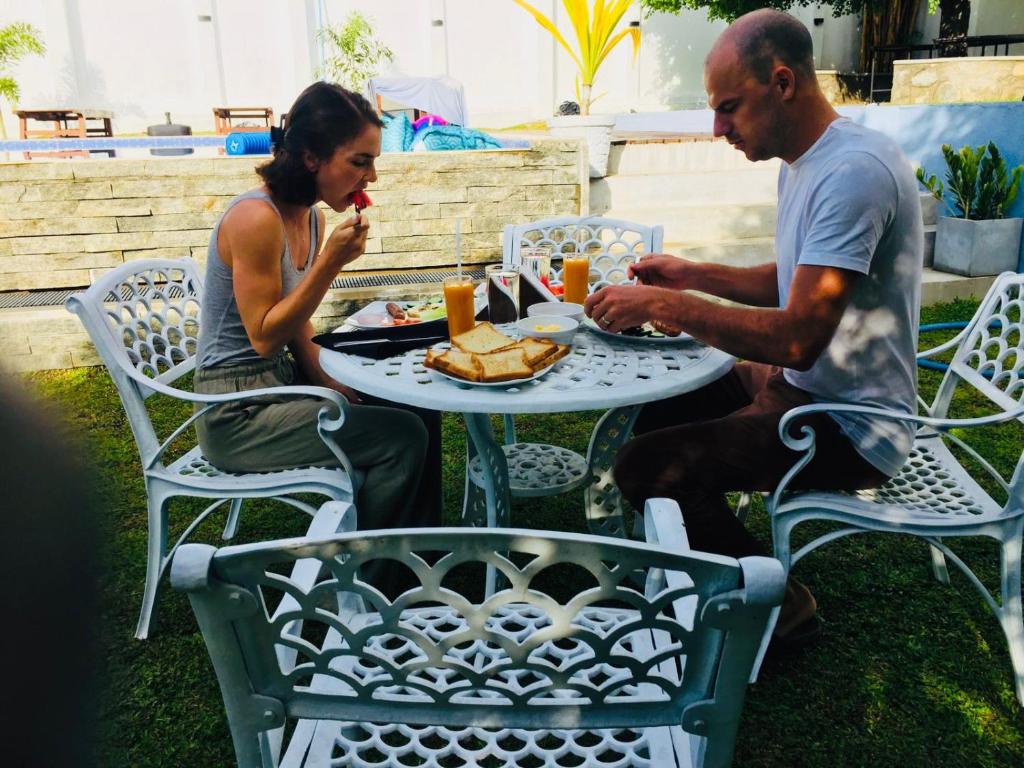 a man and woman sitting at a table eating food at The White House Resort in Wellawaya