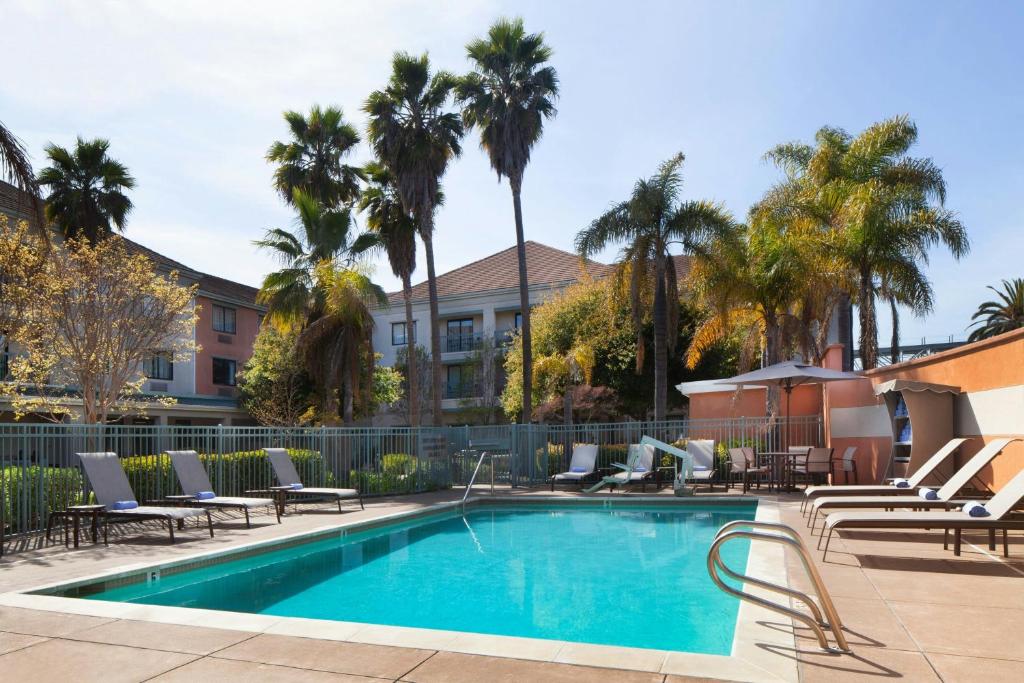 a swimming pool with lounge chairs and a resort at Courtyard by Marriott Oakland Airport in Oakland
