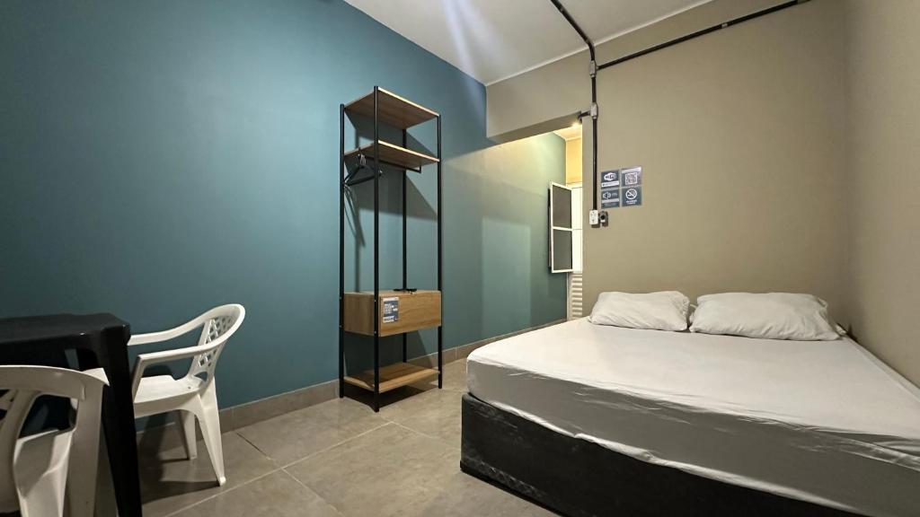 a bedroom with a bed and a desk and a chair at Suíte 03 • Praia das Pitangueiras in Guarujá