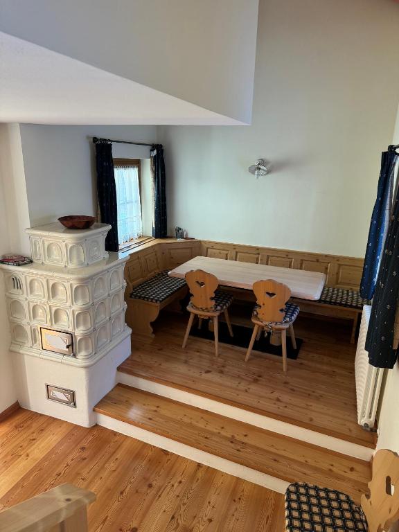 a room with a fireplace and a table and chairs at Cèsa Emily in Campitello di Fassa