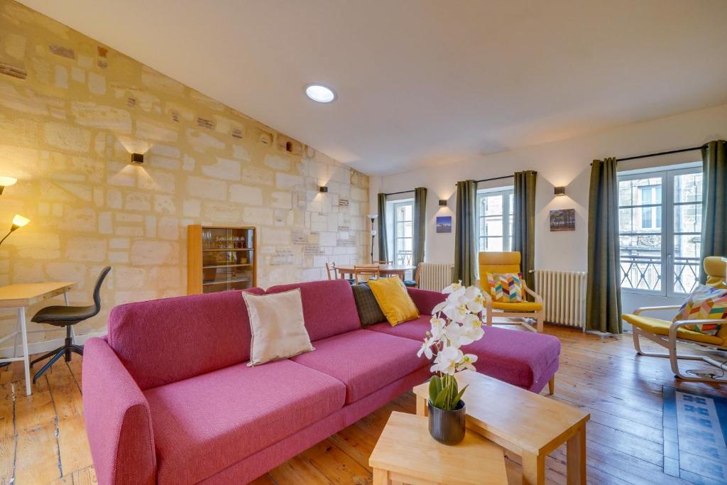 - un salon avec un canapé violet et un mur en pierre dans l'établissement L'Odéia - Chamant appt en plein coeur de Bordeaux, à Bordeaux