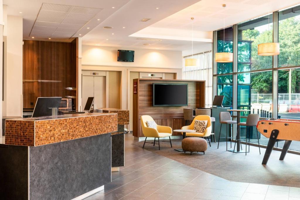 an office lobby with a bar with chairs and a tv at Courtyard by Marriott Paris Saint Denis in Saint-Denis
