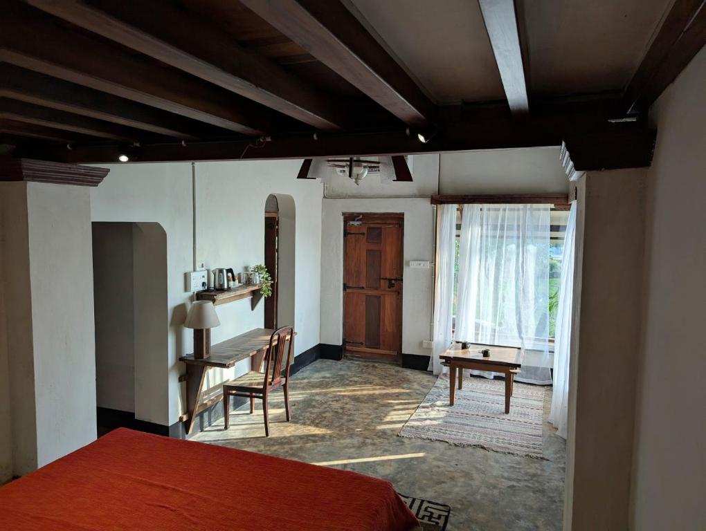 a bedroom with a bed and a desk and a window at Svarna in Udupi