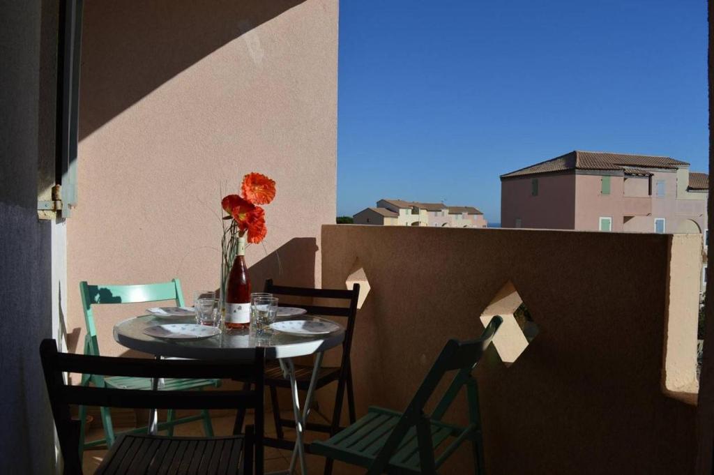 une table avec des chaises et un vase avec des fleurs dessus dans l'établissement SP520-B129 Appartement 2 pièces SAINT PIERRE LA MER, à Saint Pierre La Mer