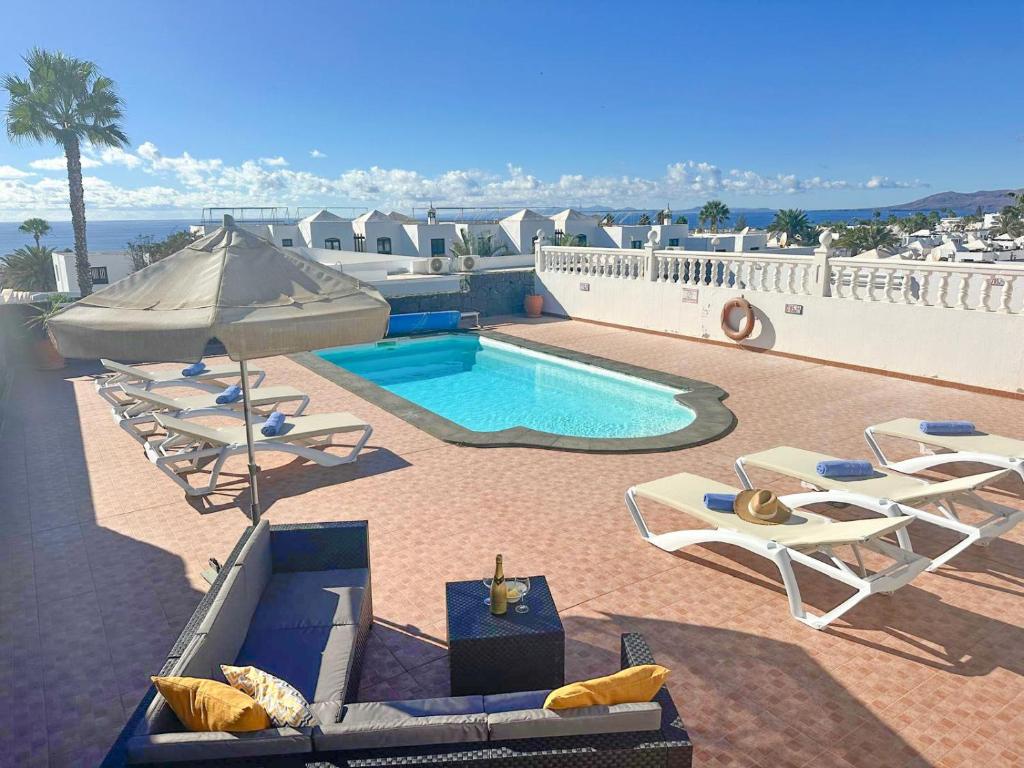 ein Swimmingpool mit Liegestühlen und Sonnenschirm in der Unterkunft Villa Siempre Mar in Puerto del Carmen