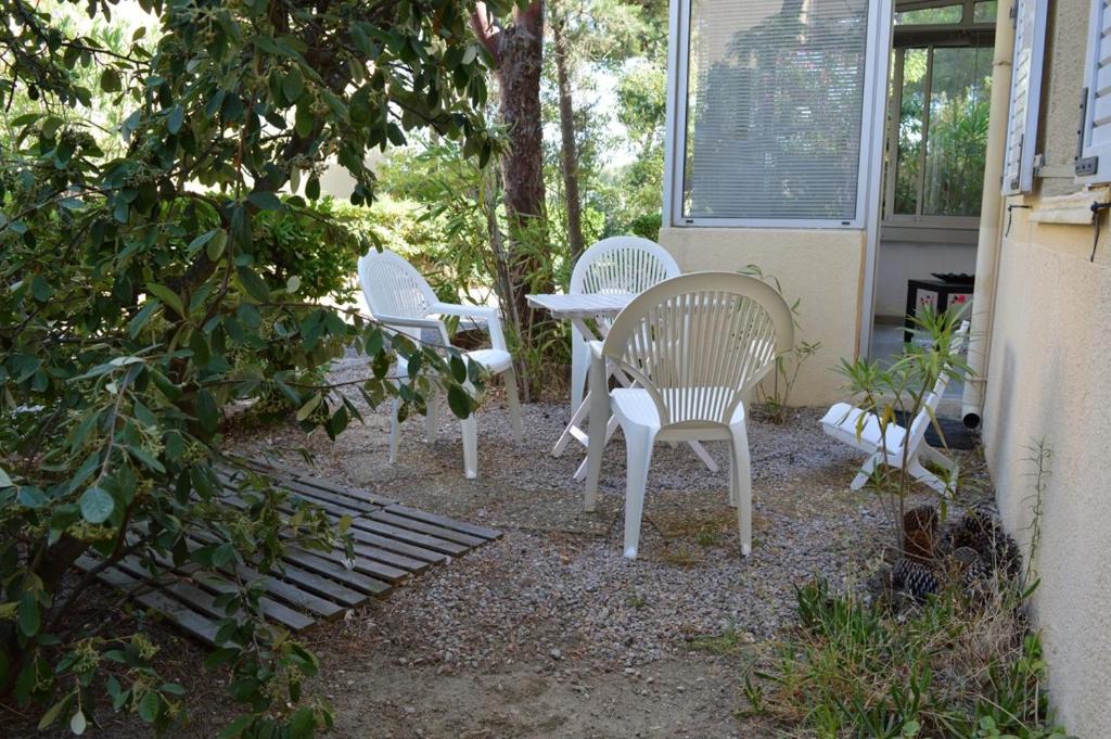 3 chaises blanches et une table dans la cour dans l'établissement Appartement studio 2 couchages ARGELES SUR MER AR450-1002, à Argelès-sur-Mer