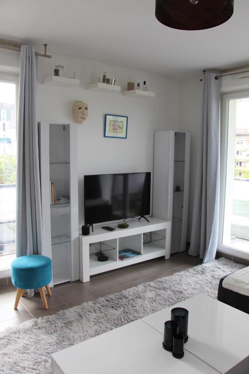 - un salon avec une télévision et un centre de divertissement blanc dans l'établissement Appartement, à Saint-Louis