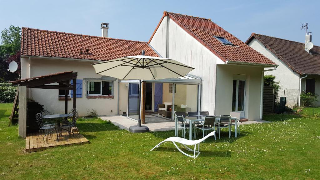 un patio avec une table, des chaises et un parasol dans l'établissement Opale les pins, à Camiers