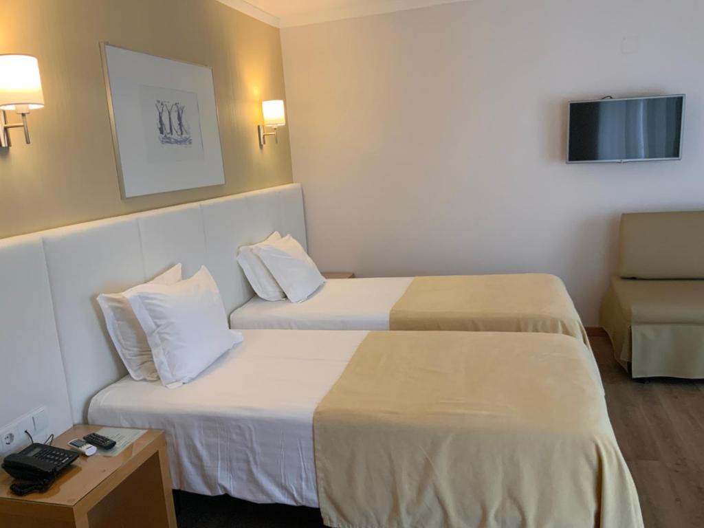 a hotel room with two beds and a chair at Hotel Mare in Nazaré