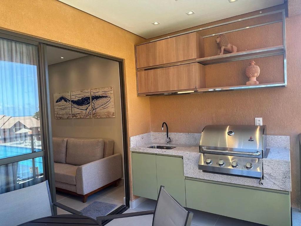 a kitchen with a stove and a sink and a couch at Flat Colina - Eco Resort Praia dos Carneiros in Tamandaré