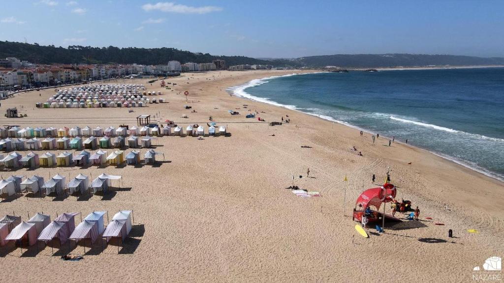 a beach with chairs and umbrellas and the ocean at Hotel Mare in Nazaré