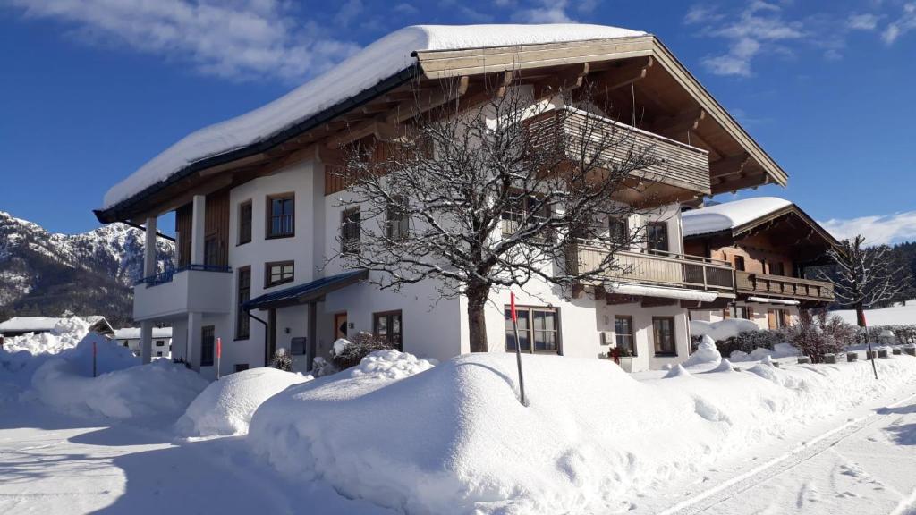 a house covered in snow with a lot of snow around it at Ferienwohnung Mittendrin in Hochfilzen