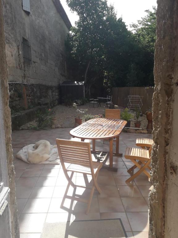- une terrasse avec une table, deux chaises et un chien dans l'établissement Maison rose, à Capestang