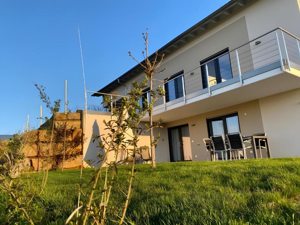 a house with a balcony and chairs in the yard at Ferienwohnungen Joachim Fischer in Vaihingen an der Enz
