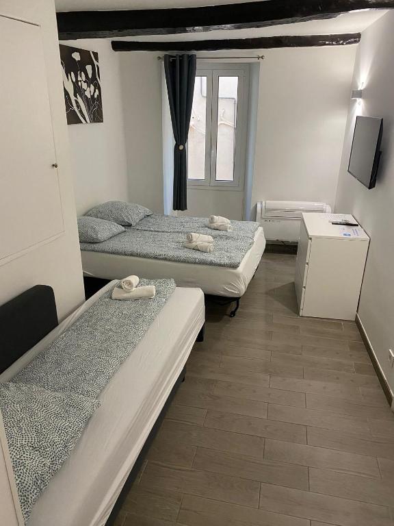 une chambre avec trois lits et une fenêtre dans l'établissement Renovated studio in the heart of the Old Town, à Menton