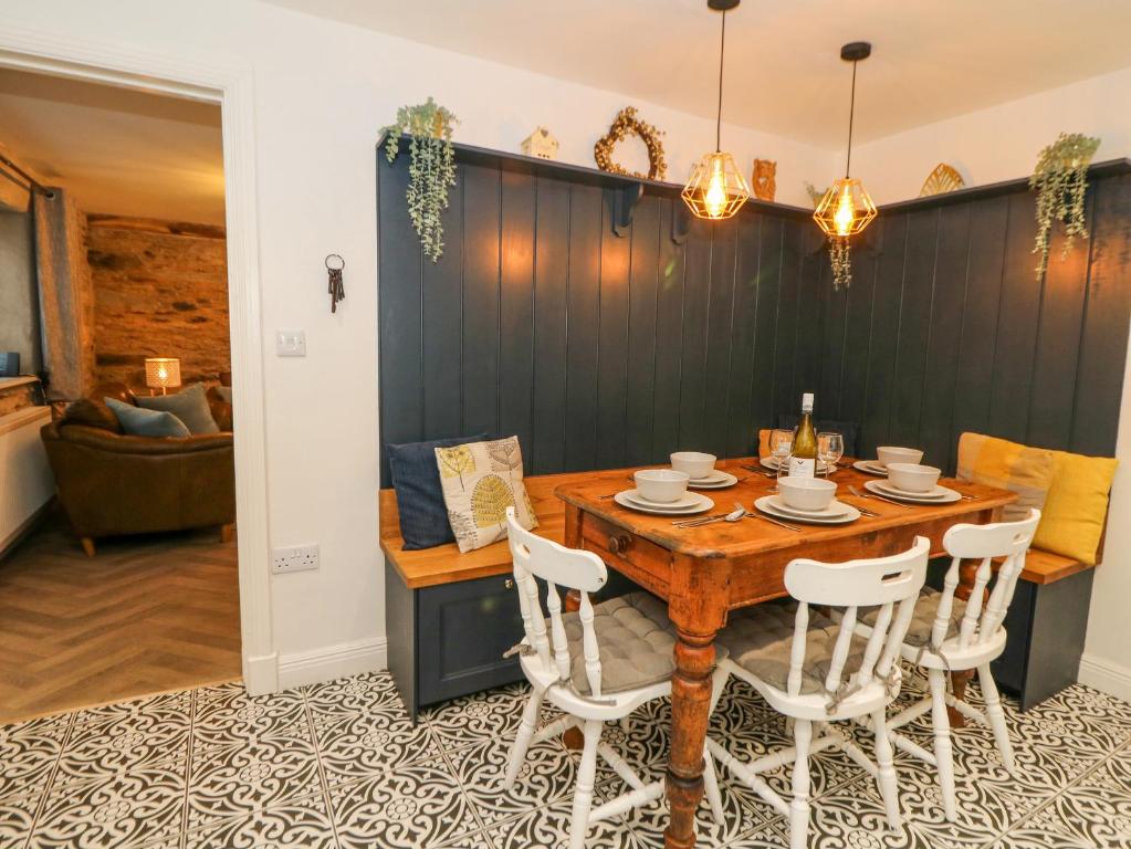 une salle à manger avec une table en bois et des chaises blanches dans l'établissement La Bastille, à Haverfordwest