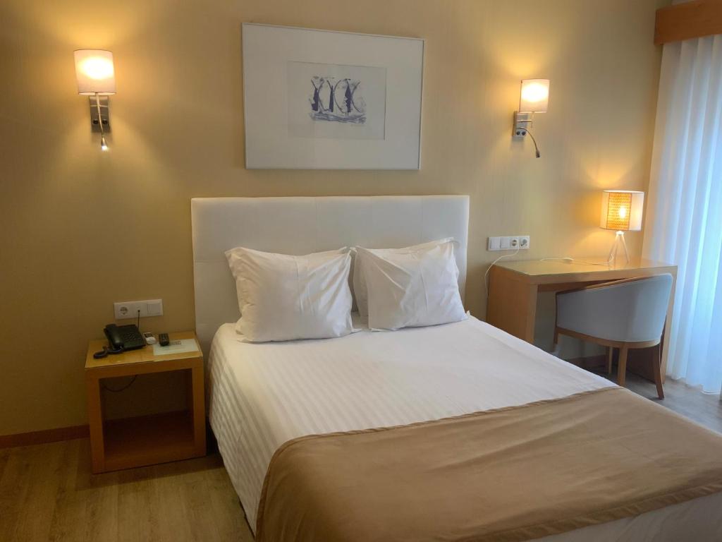 a bedroom with a bed with white sheets and pillows at Hotel Mare in Nazaré