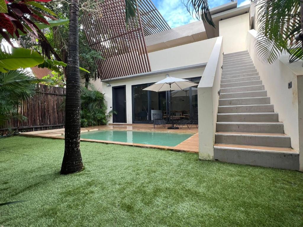 a house with a swimming pool and a palm tree at Increíble Villa 2 piscinas 4hab hasta 14 personas in Tulum