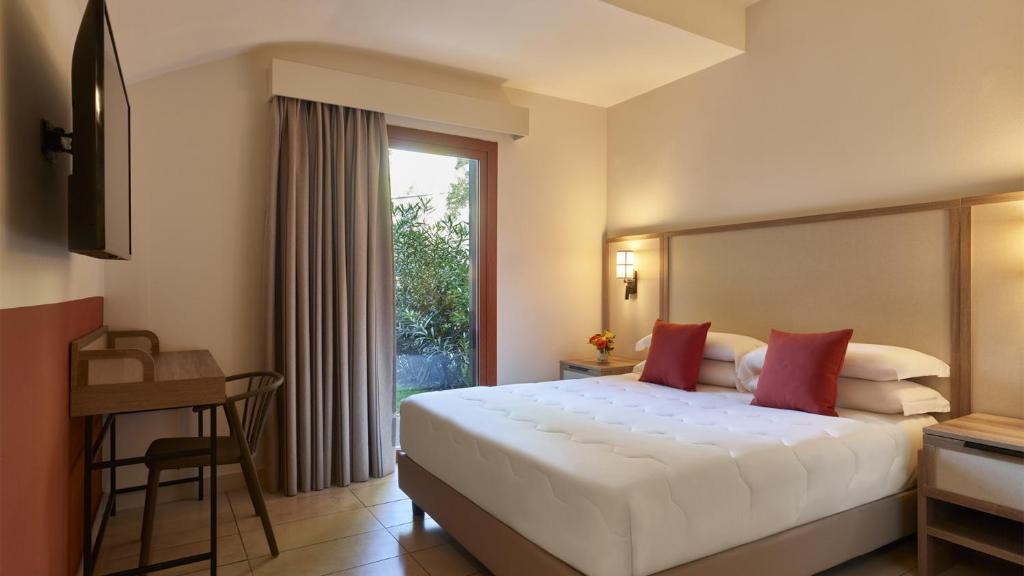 a hotel room with a large bed and a window at Calaserena Resort in Geremèas