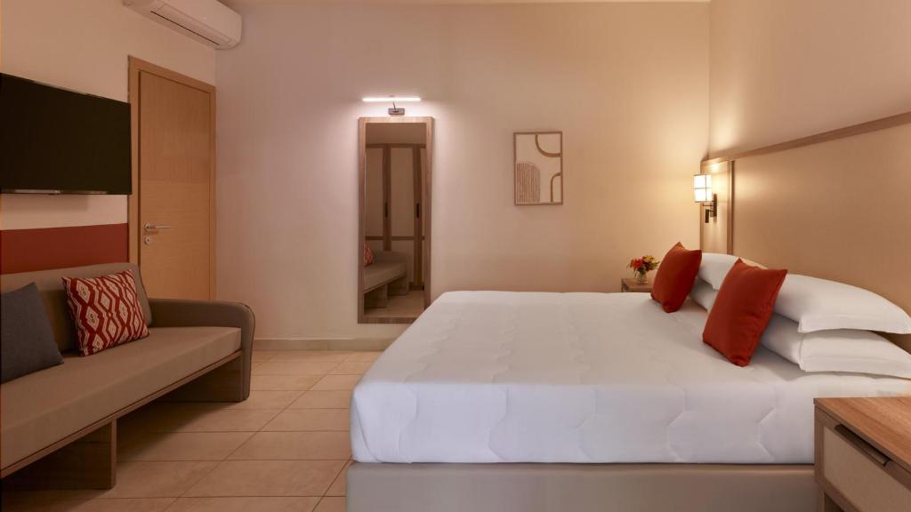 a bedroom with a large white bed and a couch at Calaserena Resort in Geremèas