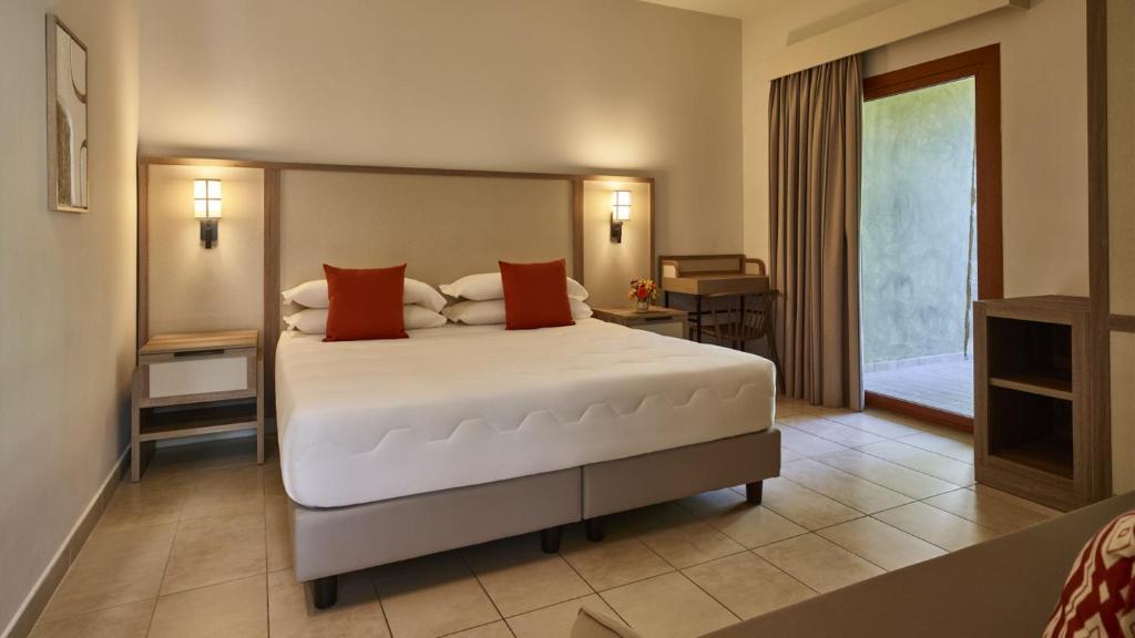 a bedroom with a large white bed with red pillows at Calaserena Resort in Geremèas
