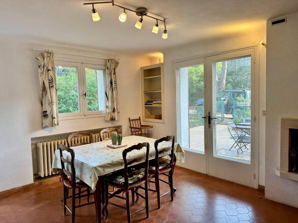 une salle à manger avec une table, des chaises et une cheminée dans l'établissement L'Orange, agréable gîte en pleine nature, à Hyères