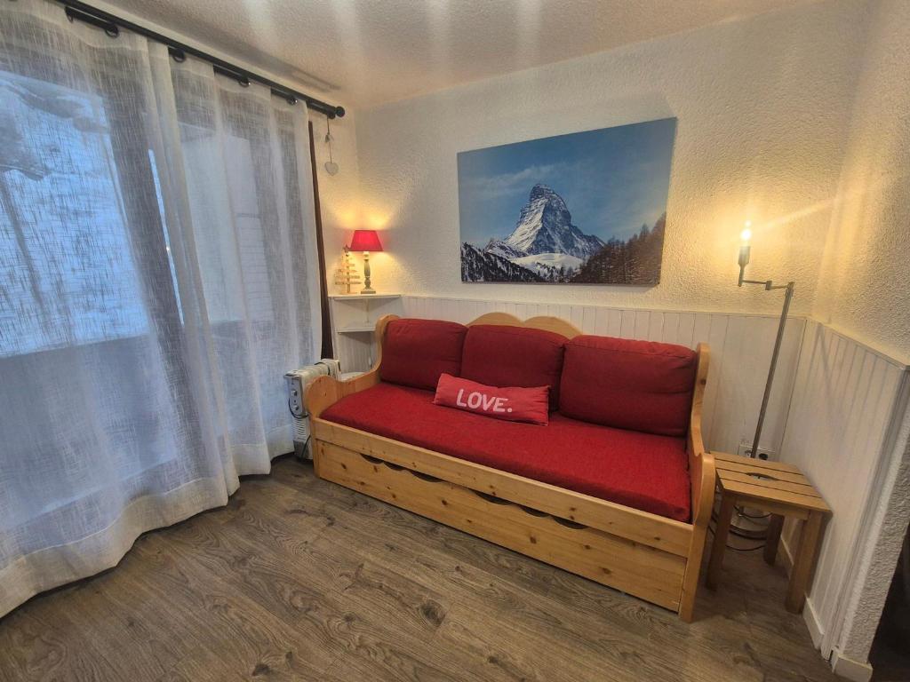 - un canapé avec un oreiller rouge dans l'établissement Studio rénové avec balcon aux pieds des pistes, WiFi, animaux permis - FR-1-502-415, à Tignes