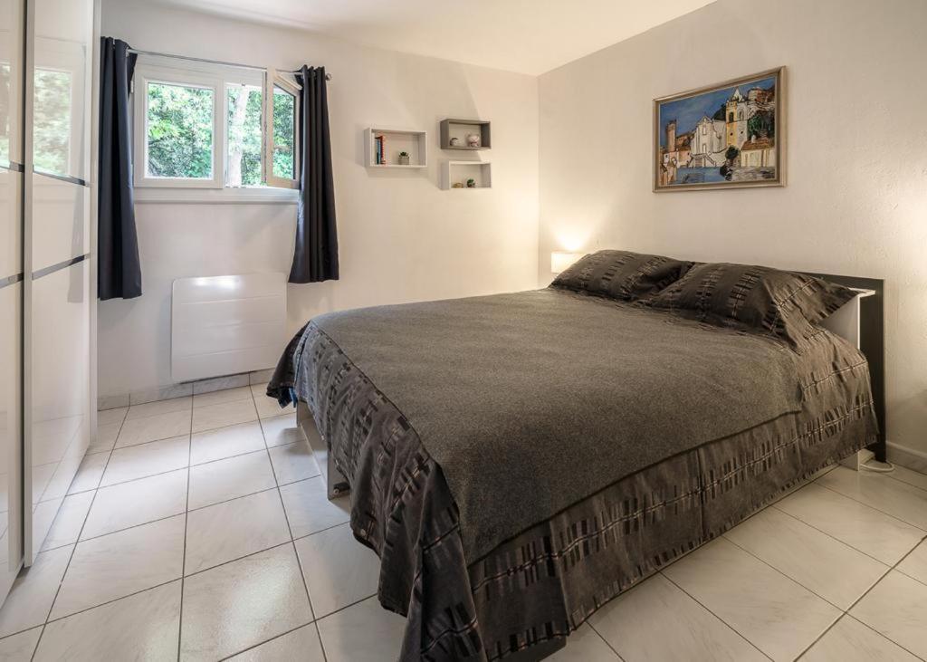 a bedroom with a large bed and a window at Rez de villa avec beau jardin et belle vue in Saint-Laurent-du-Var