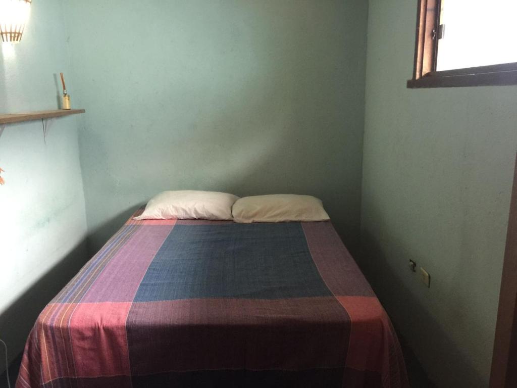 een kleine slaapkamer met een bed met een kleurrijke deken bij Casa Laranja in Arraial d'Ajuda