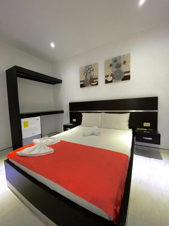 a bedroom with a large bed with a red blanket at Hotel Suite Royal in Melgar