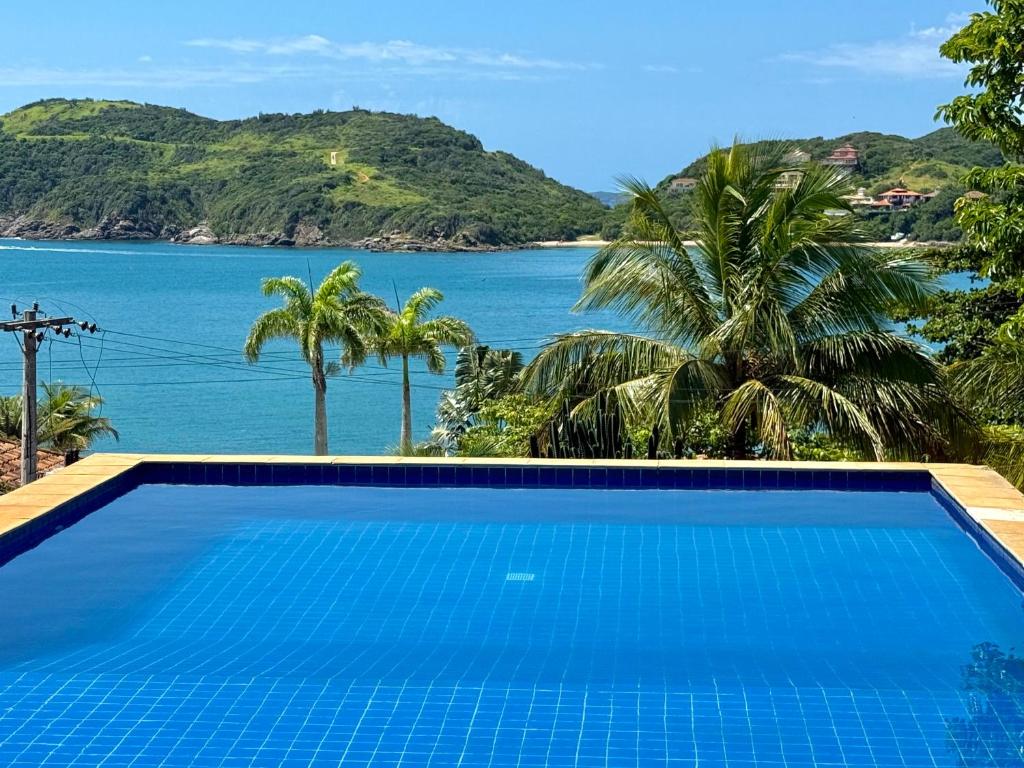 a swimming pool with a view of the ocean at Casa de CINEMA 3 suites, 50m da Praia da Ferradura in Búzios