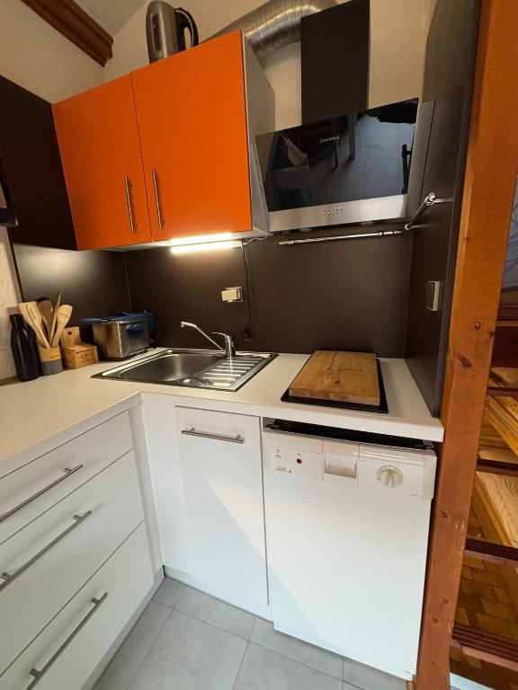 une petite cuisine avec des armoires orange et un évier dans l'établissement 5 Places Résidence Le Village, à Aragnouet
