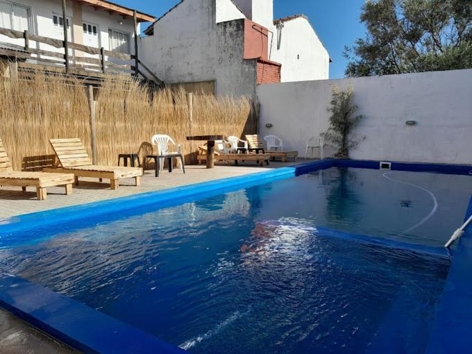 a blue swimming pool with two chairs and a table at Costa Clara Hotel in Santa Clara del Mar