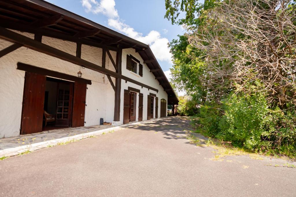 un bâtiment blanc avec un portail et des arbres sur le côté. dans l'établissement Maison familiale tradition landaise, à Andernos-les-Bains