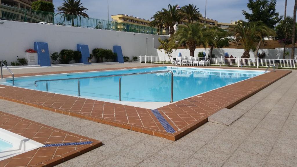 a swimming pool with a brick walkway next to a building at Nice view in Playa del Ingles