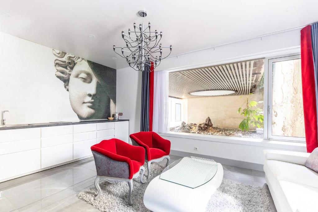 a living room with red chairs and a chandelier at Home in Paris Marais Elegant Flat in Old Paris in Paris