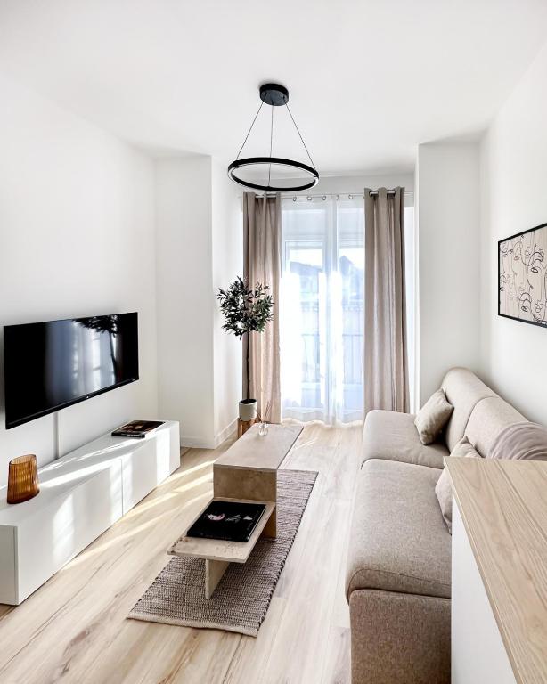 un salon blanc avec un canapé et une télévision dans l'établissement 3P au coeur de Juan les Pins, à Antibes