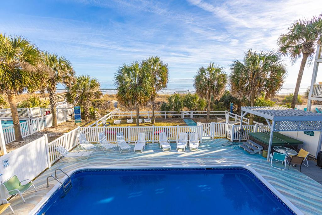 una piscina con sillas y palmeras en Lavish Accessible, On Ocean, 4 King Beds, Huge Private Pool, Yard, Spa, Patio, BBQ, & Game Tables, en Myrtle Beach