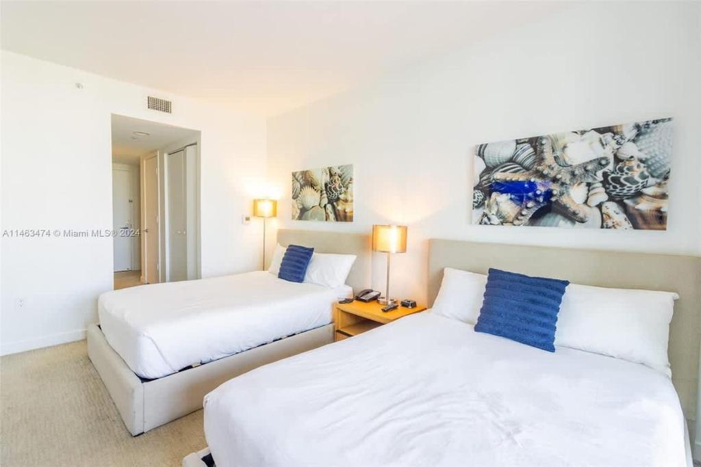 Dos camas en una habitación de hotel con blanco y azul en Luxury Suite on Beachwalk with Pool Gym & Beach, en Hallandale Beach