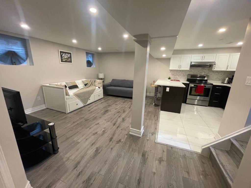 a living room with a couch and a kitchen at CozyHaven A private entrance, comfy basement apartment in Mississauga with free parking Conveniently located with easy access to the airport downtown Toronto major malls and highways for a seamless stay in Mississauga