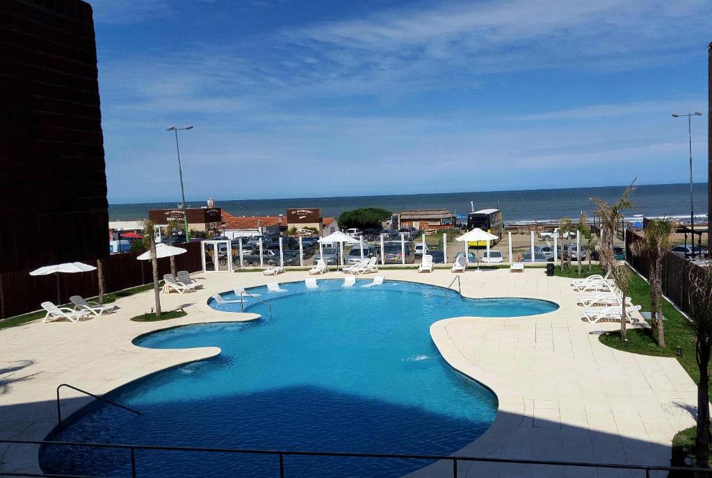 a swimming pool with chairs and the ocean in the background at Hotel Reviens in Pinamar