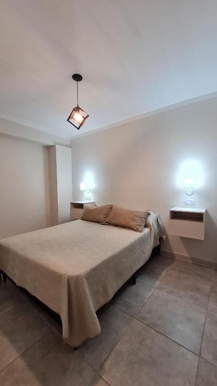 a bedroom with a bed with two lights on the wall at Complejo Aviv Centro in La Rioja
