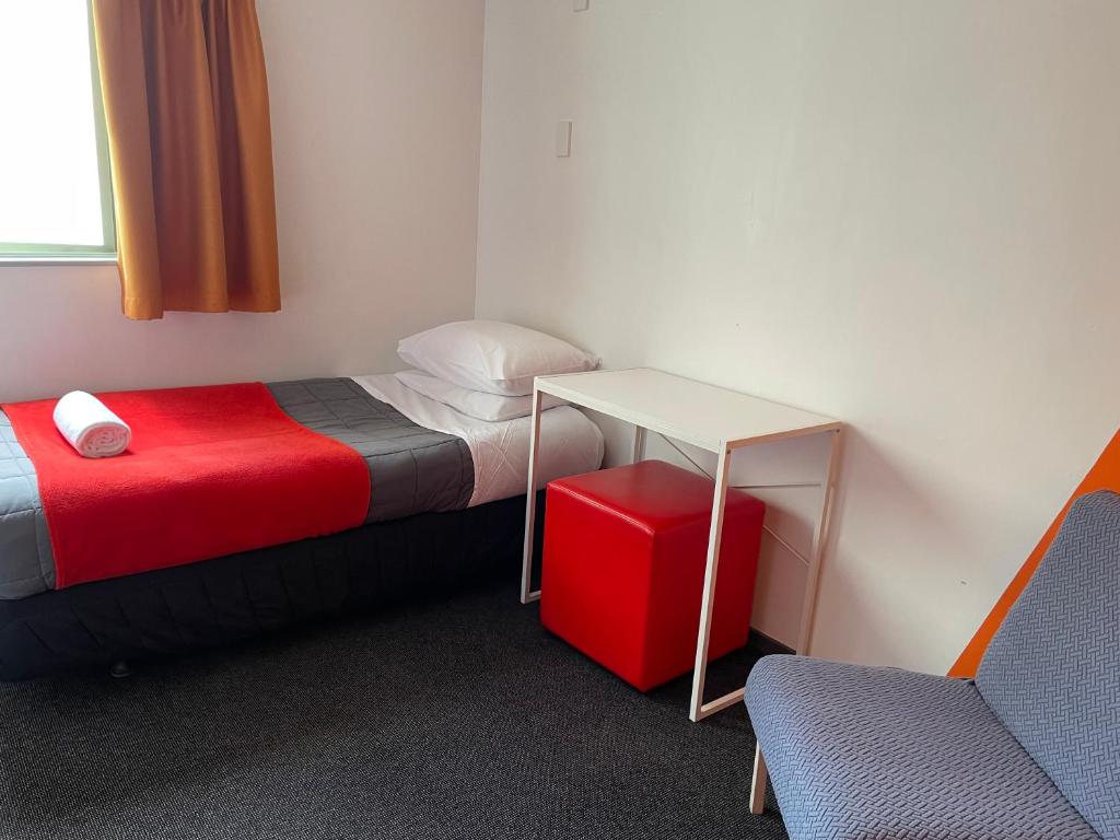 a room with two beds and a table and a chair at YHA Nelson in Nelson