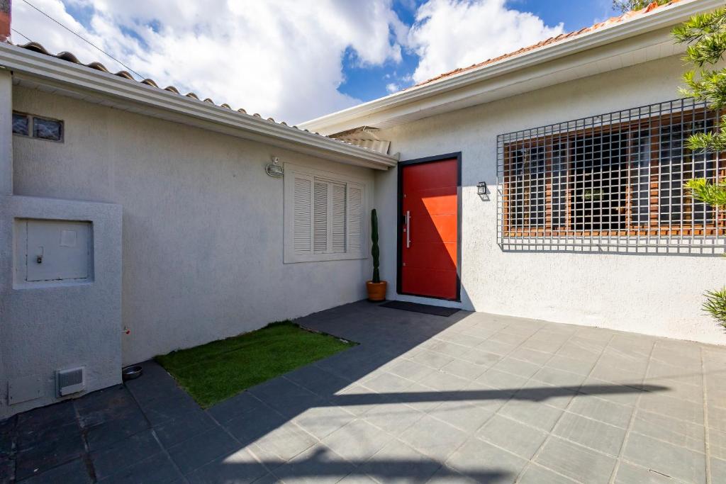 uma casa branca com uma porta vermelha e um quintal em Casa Completa com garagem em Curitiba