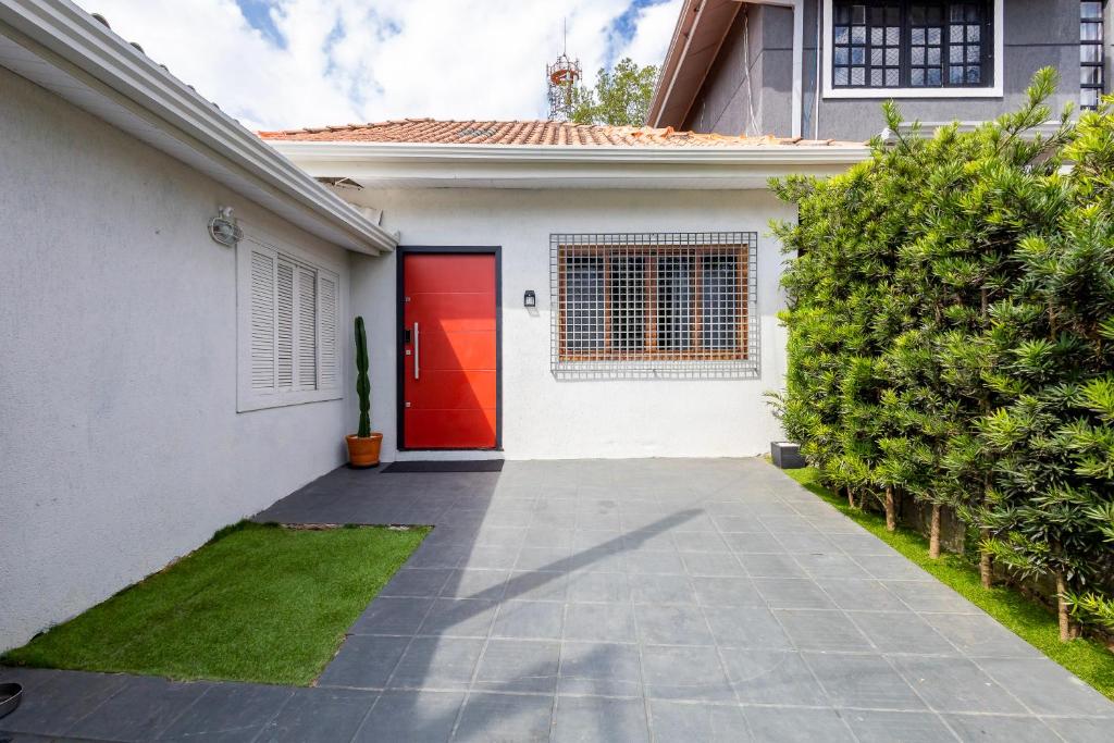 a red door on a white house with a driveway at Casa Completa com garagem in Curitiba